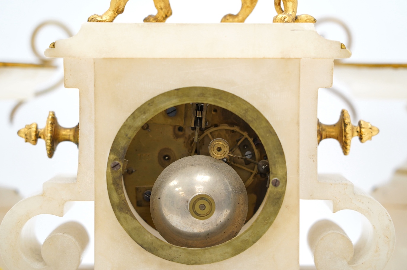 An early 20th century alabaster and gilt metal clock garniture with enamel panels, surmounted with a lion, with pendulum, no key, clock 30cm high. Condition - poor